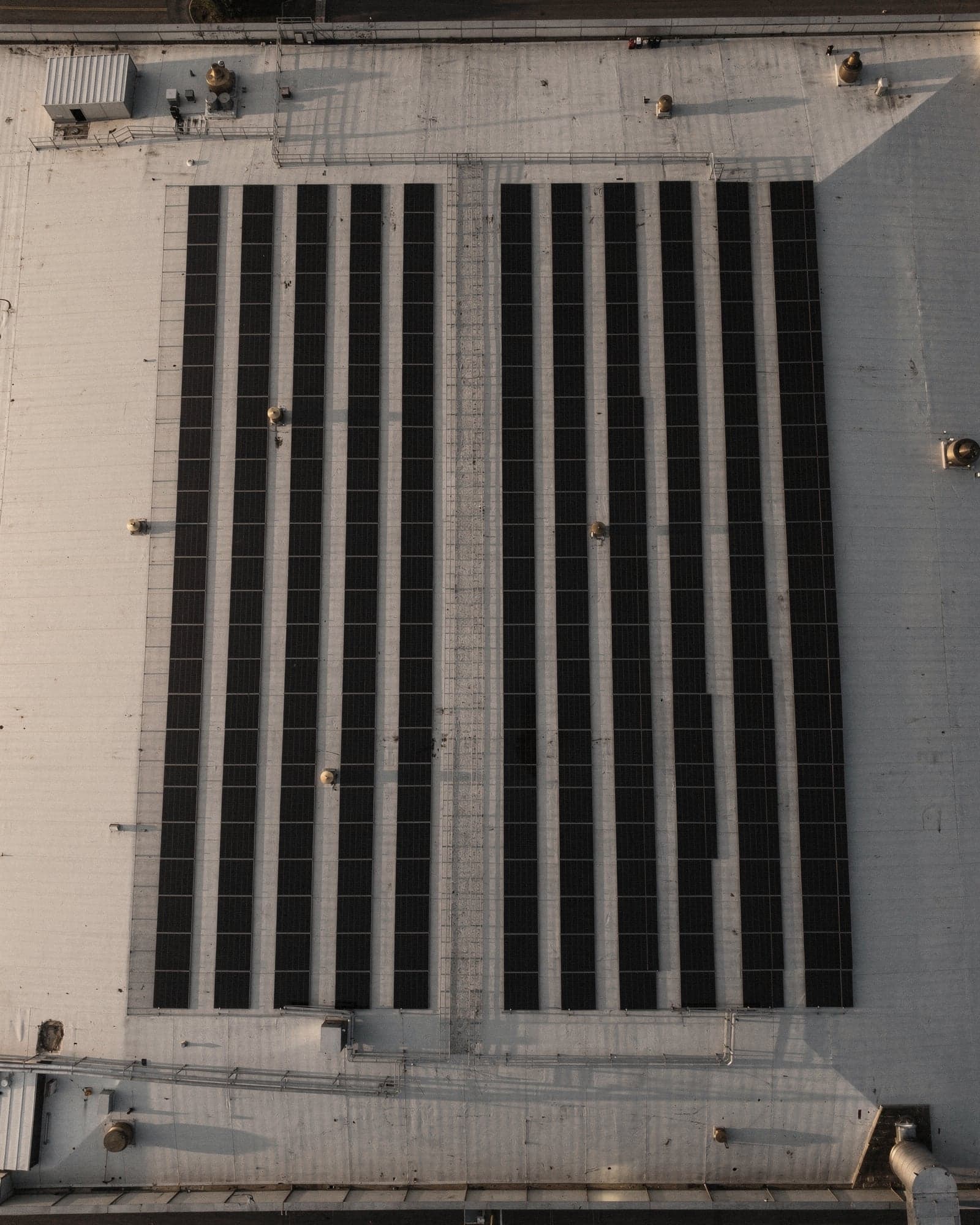Cubierta de una nave industrial con filas de paneles solares vistas desde un dron