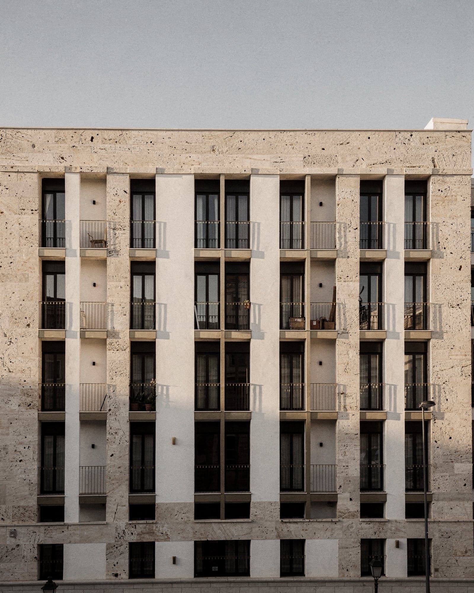 Fachada de un edificio residencial mediterráneo con balcones y ventanales en retícula